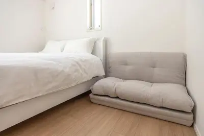 a bed and a chair in a room at \u6771\u4eac\u65b0\u7bc985\u5e73\u7c73\u99c5\u5f92\u6b696\u5206\u6700\u59278\u540d\u7121\u6599\u99d0\u8eca\u5834\u6771\u4eac\u4e0a\u91ce\u79cb\u8449\u539f\u99c5\u76f4\u901a in Tokyo