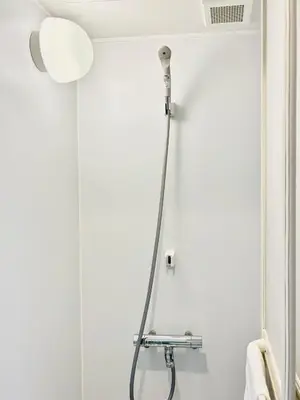 a shower head in a bathroom with a white wall at GLOU Shinjuku Family - Urban Stay in Tokyo Shinjuku Area, Walking distance of Kabukicho in Tokyo
