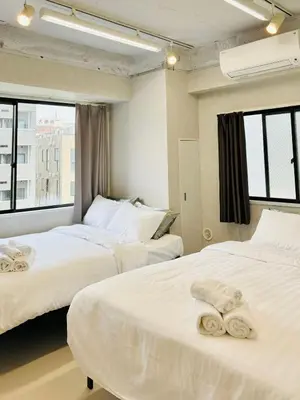 two beds in a hotel room with towels on them at GLOU Shinjuku Family - Urban Stay in Tokyo Shinjuku Area, Walking distance of Kabukicho in Tokyo