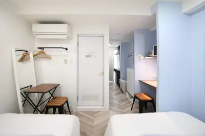 a bedroom with two beds and a table with two chairs at Shibuya WAVE 302 in Tokyo
