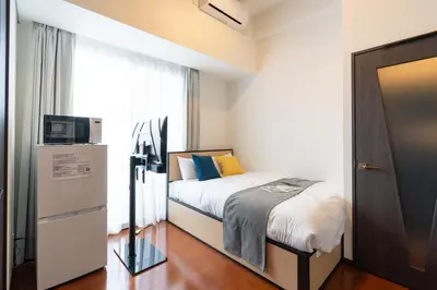 a small bedroom with a bed and a microwave at \u30ec\u30ea\u30aa\u30f3\u4e0b\u843d\u5408 in Tokyo