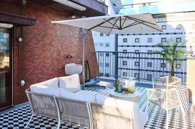 a patio with a couch and an umbrella on a balcony at Central Shinjuku apartment with beautiful city view 3stops to Shibuya in Tokyo