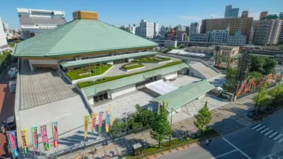 a large building with a green roof in a city at SKY BLUE HOUSE Asakusabashi in Tokyo