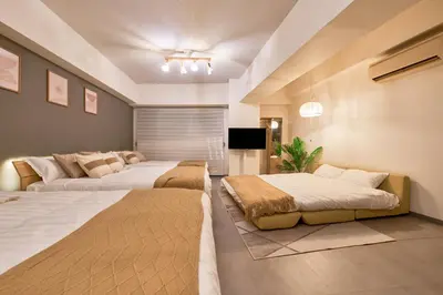a bedroom with two beds and a flat screen tv at Shinjuku Waseda Stay in Tokyo