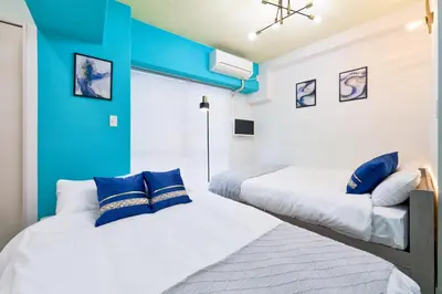 two beds in a room with blue walls at Shinjuku Waseda Stay in Tokyo
