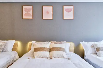 a bedroom with two beds and three pictures on the wall at Shinjuku Waseda Stay in Tokyo