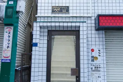 a white tiled building with a door and a sign at King bed house 5mins from Ikebukuro by train in Tokyo