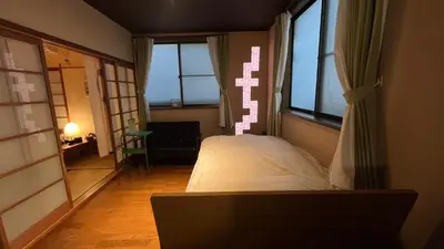 a bedroom with a bed in a room with windows at Artful Cats house in Tokyo