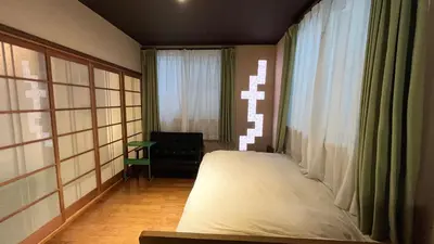 a bedroom with a bed and a window and a chair at Artful Cats house in Tokyo