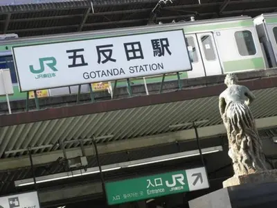 a statue in front of a subway station with a train at Village Gotanda in Tokyo