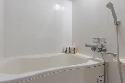 a white bathroom with a tub and a sink at Village Gotanda in Tokyo