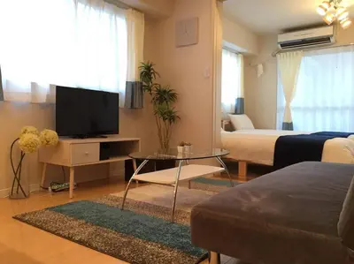 a living room with a tv and a bed and a couch at Village Gotanda in Tokyo