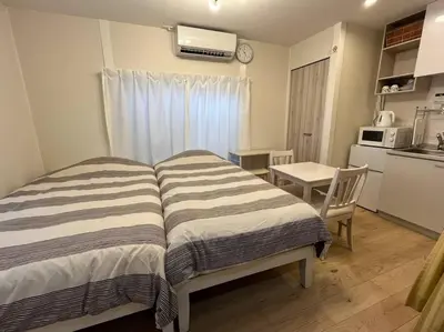 a room with a bed and a table and a kitchen at Cozy INN \u897f\u54c1\u5ddd201 in Tokyo