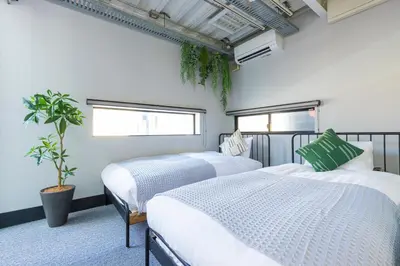 a bedroom with two beds and a potted plant at Pufuka Mukojima 1 in Tokyo