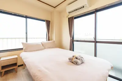 a teddy bear sitting on a bed in a room with windows at \u9759\u5fc3\u5bbfTranquil Retreat 4F\u6674\u7a7a\u5854\u76f4\u8fbe\u4e1c\u4eac\u6cb3\u666f\u6c11\u5bbf in Tokyo