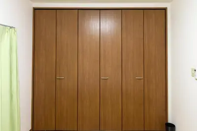 a closet with wooden doors in a room at \u6c60\u888b\u672c\u753a\u4e00\u8ed2\u5bb6 \u6700\u59276\u540d WiFi \u5317\u6c60\u888b\u99c5\u5f92\u6b696\u5206 \u6c60\u888b\u99c5\u96fb\u8eca1\u5206 in Tokyo