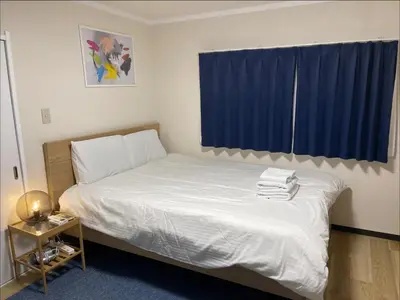 a bedroom with a white bed with a blue curtain at self-check in-\u65b0\u5927\u4e45\u4fdd\u30de\u30f3\u30b7\u30e7\u30f3 in Tokyo