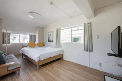 a bedroom with a bed with yellow pillows and a tv at self-check in-\u65b0\u5927\u4e45\u4fdd\u30de\u30f3\u30b7\u30e7\u30f3 in Tokyo