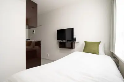 a bedroom with a white bed and a flat screen tv at CH RESiDENCE \u559c\u4e45\u4e95\u753a in Tokyo