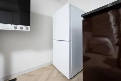 a white refrigerator in a kitchen next to a wall at CH RESiDENCE \u559c\u4e45\u4e95\u753a in Tokyo