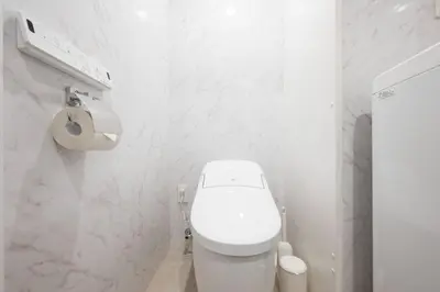 a white bathroom with a toilet and a paper dispenser at CH RESiDENCE \u559c\u4e45\u4e95\u753a in Tokyo