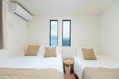 two beds in a room with two windows at \u798f\u5409\u5c4b in Tokyo