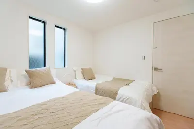 two beds in a white room with windows at \u798f\u5409\u5c4b in Tokyo