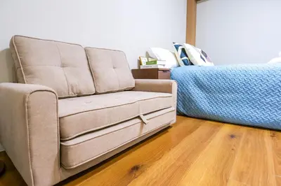 a couch in a living room next to a bed at Maru 5 Inn in Tokyo