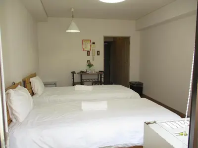 a bedroom with two white beds and a table at \u30e9\u30a4\u30aa\u30f3\u30ba\u30de\u30f3\u30b7\u30e7\u30f3\u9053\u7384\u5742a in Tokyo