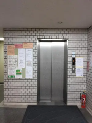 a metal elevator door in a brick wall at \u30e9\u30a4\u30aa\u30f3\u30ba\u30de\u30f3\u30b7\u30e7\u30f3\u9053\u7384\u5742a in Tokyo