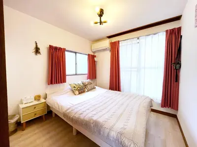 a bedroom with a bed and a window with red curtains at \u672c\u753a1\u4e01\u76eeB Honcho 1-chome b in Tokyo