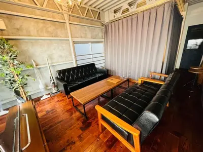 a living room with a black couch and a wooden table at Rakuna Inn \u904a Kinshicho in Tokyo