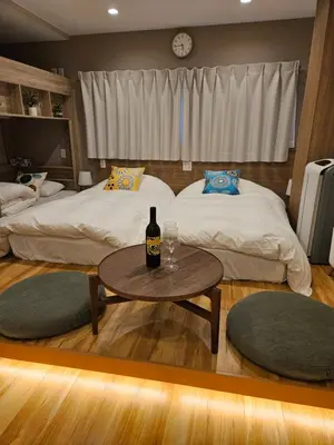 a bedroom with two beds and a table with a bottle of wine at Asakusa Stay in Tokyo