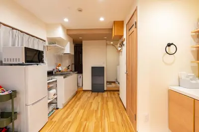 a kitchen with white cabinets and a wooden floor at Asakusa Stay in Tokyo