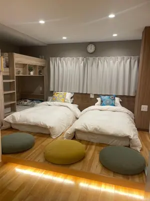 a bedroom with two beds and a clock on the wall at Asakusa Stay in Tokyo