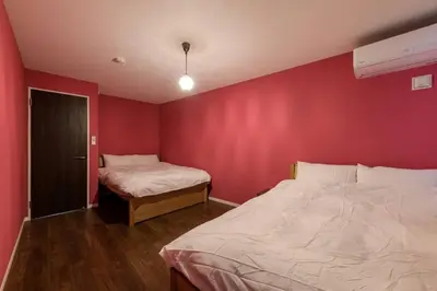 a bedroom with two beds and a red wall at Rakuna Inn \u52d5 Sasazuka in Tokyo