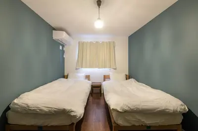 two beds in a small room with a window at Rakuna Inn \u52d5 Sasazuka in Tokyo