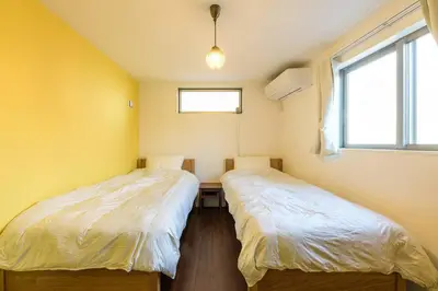 two twin beds in a room with a window at Rakuna Inn \u52d5 Sasazuka in Tokyo