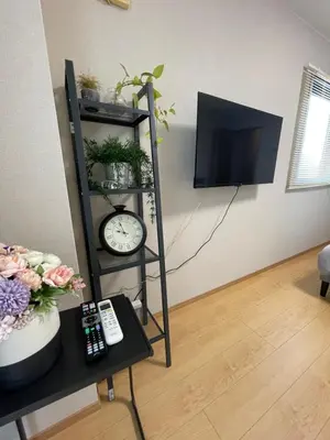 a room with a shelf with a clock and a tv at \u65b0\u5c0f\u5ca9\u30c7\u30e1\u30c6\u30eb303 in Tokyo