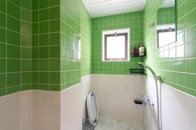 a green tiled bathroom with a shower and a toilet at Asakusa Stay in Tokyo