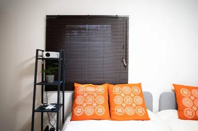 a room with a bed with orange pillows and a window at \u65b0\u5c0f\u5ca9\u99c5\u5f92\u6b693\u5206\u30c7\u30e1\u30c6\u30eb301 in Tokyo