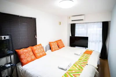 a bedroom with a bed with orange and white pillows at \u65b0\u5c0f\u5ca9\u99c5\u5f92\u6b693\u5206\u30c7\u30e1\u30c6\u30eb301 in Tokyo