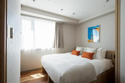 a bedroom with a large white bed with orange pillows at Section L Shimbashi West in Tokyo