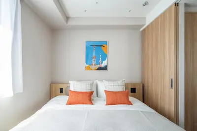 a bedroom with a white bed with orange pillows at Section L Shimbashi West in Tokyo