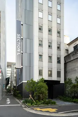 a white building with a sign on the side of it at Section L Shimbashi West in Tokyo