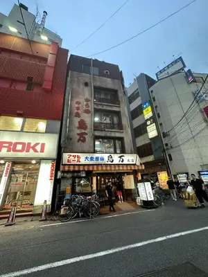 a city street with tall buildings with bikes parked on the sidewalk at West Kamata 5 \u897f\u84b2\u672c\u5bb6 in Tokyo