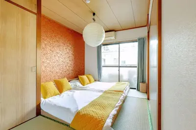 a bedroom with a bed with yellow pillows and a window at \u7acb\u77f35\u4e01\u76eem201 in Tokyo