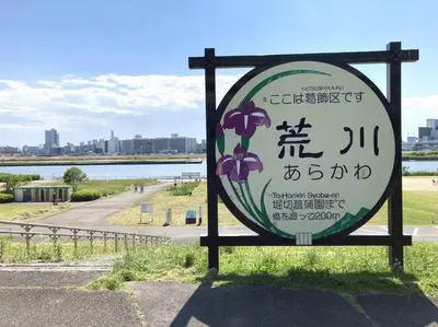 a sign with purple flowers on it next to a body of water at \u7acb\u77f35\u4e01\u76eem402 in Tokyo