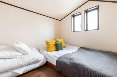 a bedroom with two beds and two windows at \u5f25\u751f\u753a1\u4e01\u76ee202 in Tokyo