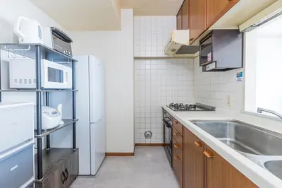 a small kitchen with a sink and a refrigerator at Spacious 1120feet , 3-Bedroom Apartment near Ikebukuro, 2 Minutes to Train in Tokyo